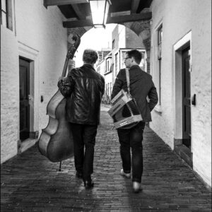 Philip Baumgarten en Peter Pot lopen door een poortje met hun instrumenten.